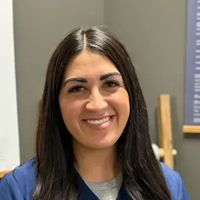 Person with long, straight dark hair wearing a dark-colored scrub top