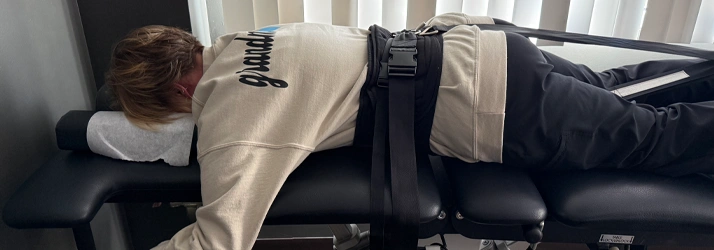 Person lying face‑down on a padded chiropractic traction table