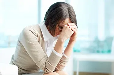 Person sitting with their head resting on both hands