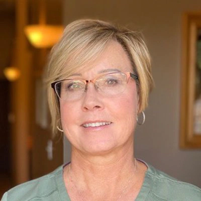 Person with short, light-colored hair wearing a light green top