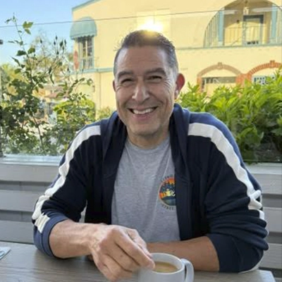 Dr. Anthony Becerra wearing a blue jacket and holding a coffee.