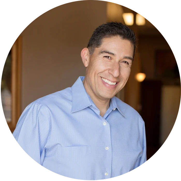 Dr. Anthony Becerra wearing a light blue collared shirt standing indoors